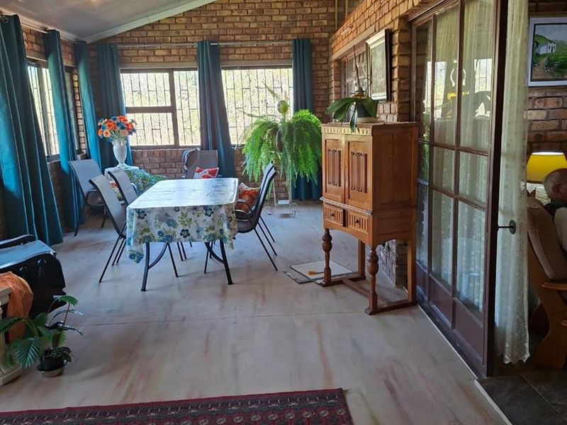 A spacious enclosed patio featuring exposed brick walls, a high sloped ceiling, and large sliding glass doors providing access to the interior living area.