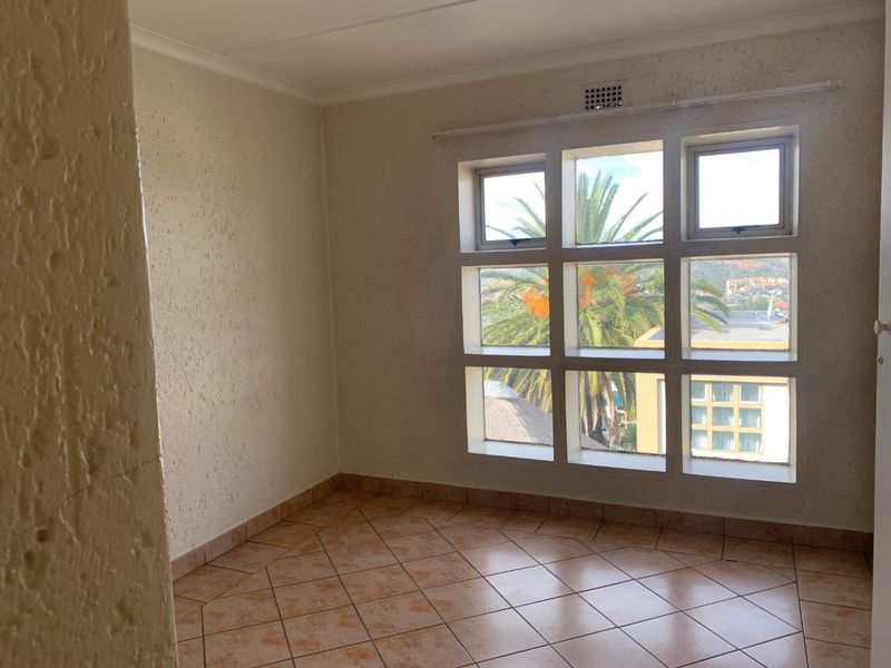An empty bedroom featuring tiled flooring and a large multi-pane window with exterior views.