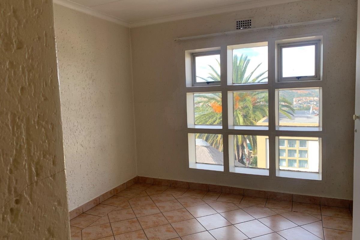 An empty bedroom featuring tiled flooring and a large multi-pane window with exterior views.