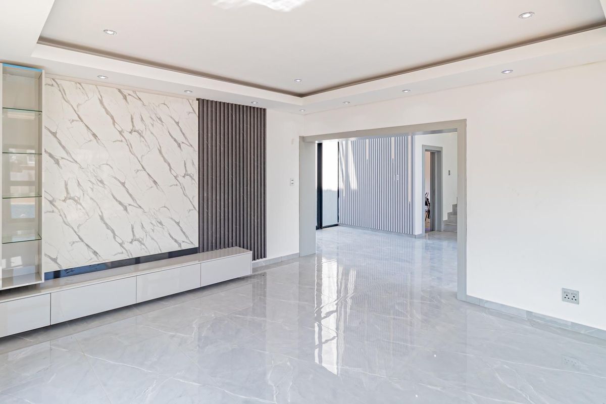 Modern living room featuring polished marble-look floor tiles, a built-in media wall with marble and timber slat detailing, and recessed ceiling lighting.