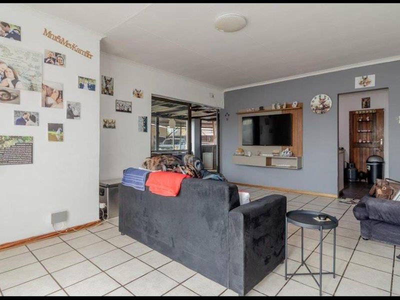 A living room featuring tiled flooring, a built-in media console, and a sliding glass door leading to an outdoor area.
