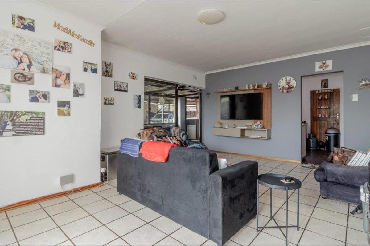 A living room featuring tiled flooring, a built-in media console, and a sliding glass door leading to an outdoor area.