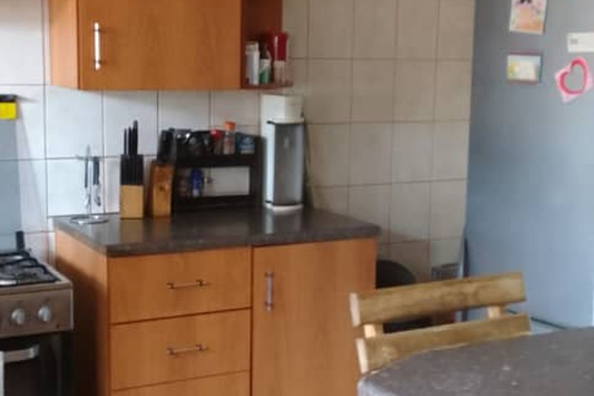 A functional kitchen area featuring wooden cabinetry, tiled splashbacks, and a built-in stove, offering a practical layout for daily meal preparation.