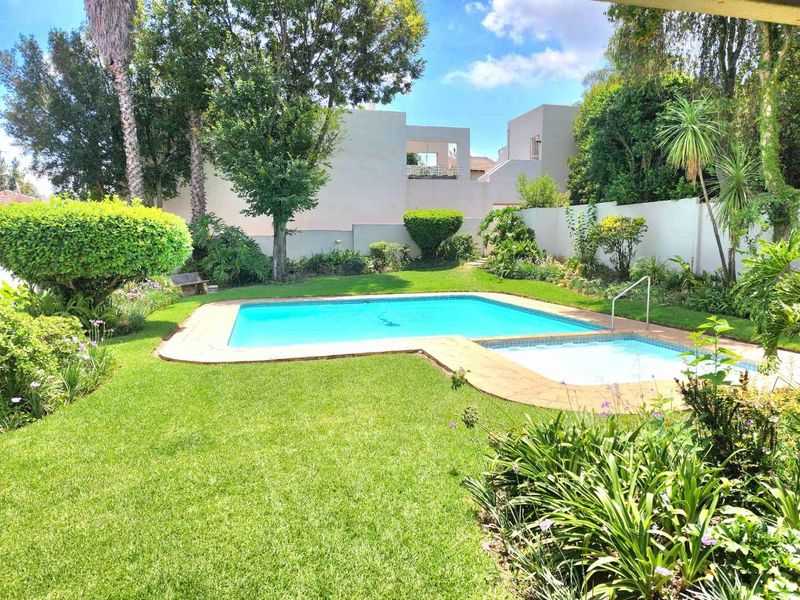 A well-maintained private swimming pool area featuring a landscaped garden, paved surround, and secure boundary walls, perfect for outdoor relaxation.