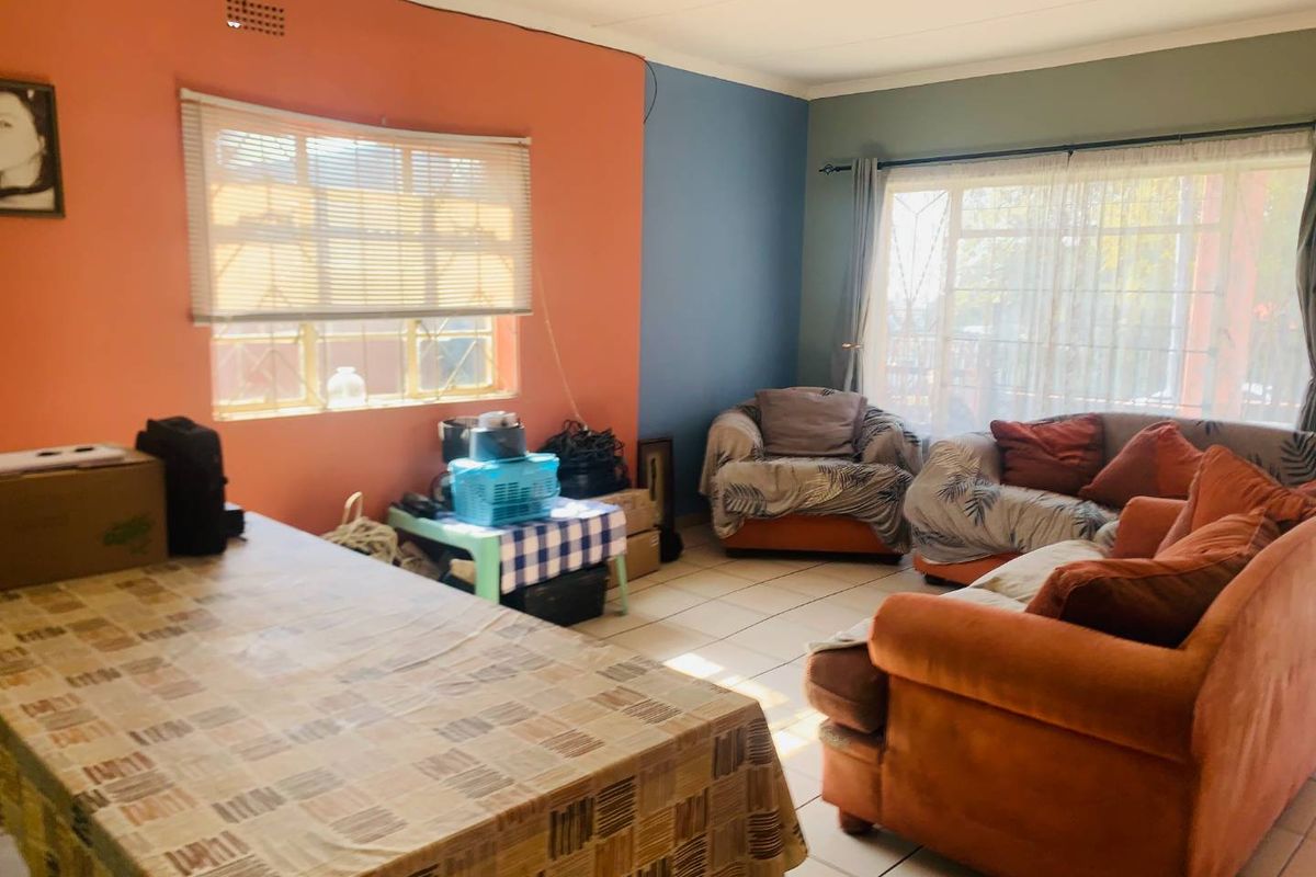 A spacious living room featuring tiled flooring and large windows, offering a bright and functional layout ready for modern updates.