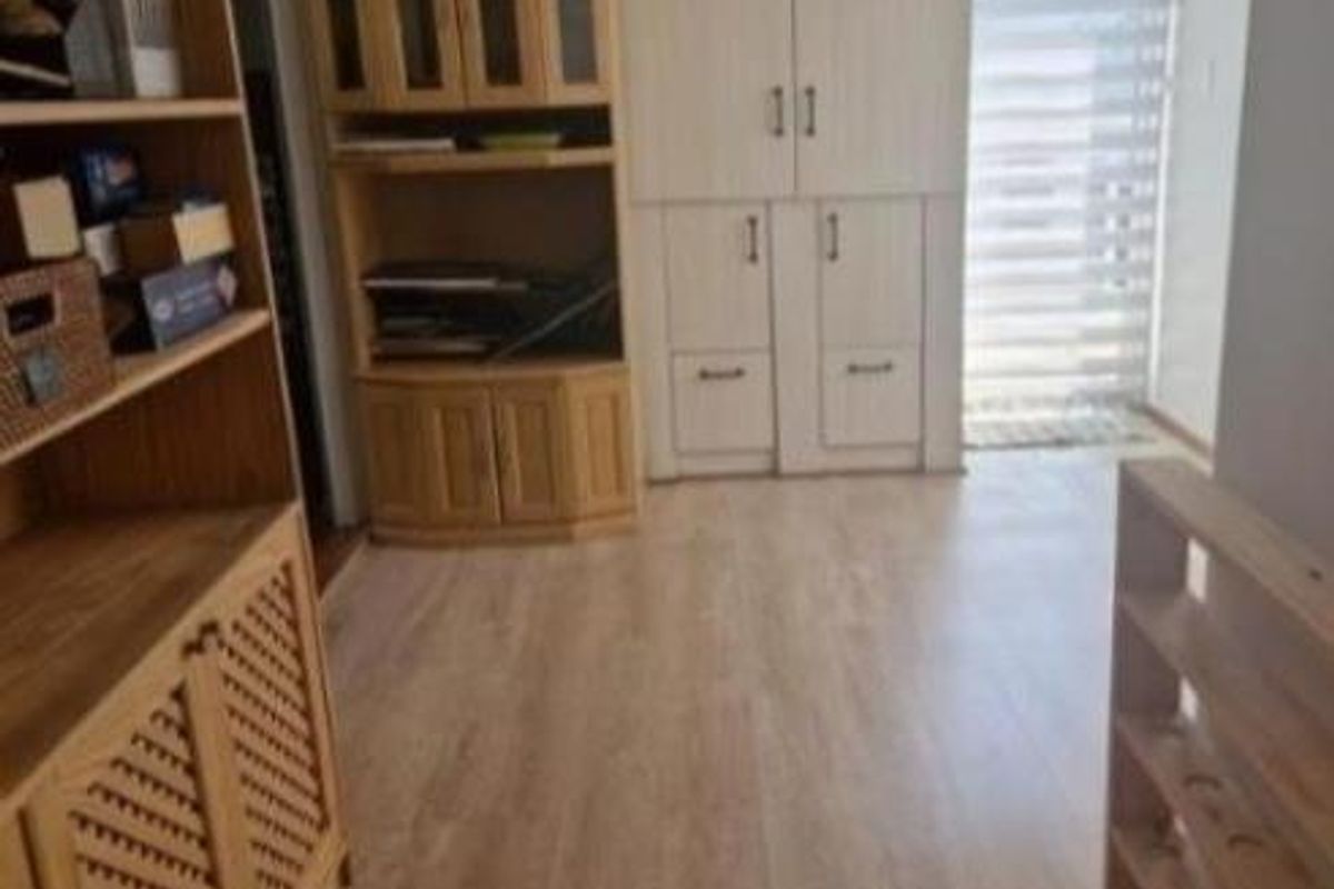 A functional living area featuring light wood-look laminate flooring and built-in cabinetry, providing ample storage space and a bright, neutral aesthetic.