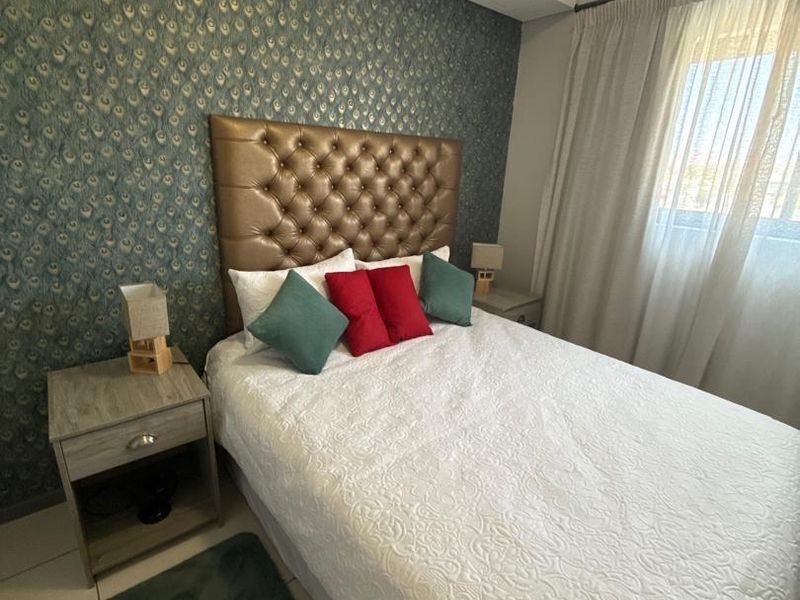 A well-maintained bedroom featuring tiled flooring and a decorative patterned feature wall, providing a comfortable and inviting sleeping space.