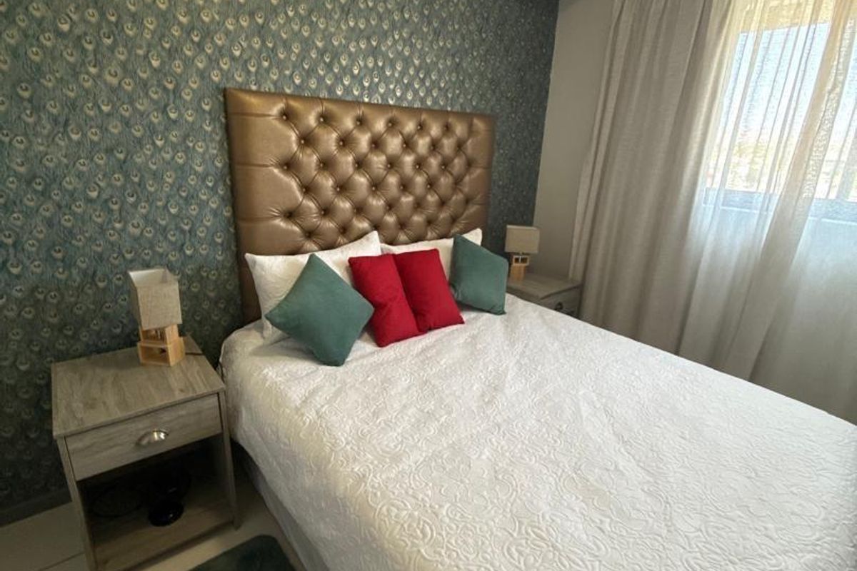 A well-maintained bedroom featuring tiled flooring and a decorative patterned feature wall, providing a comfortable and inviting sleeping space.