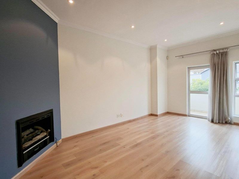 Spacious living room featuring laminate flooring, a built-in fireplace with a feature wall, recessed lighting, and direct access to an outdoor area.