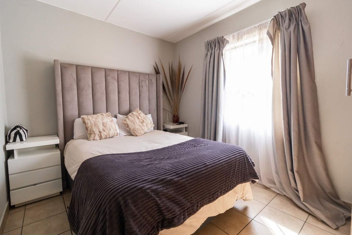 A well-lit bedroom featuring tiled flooring and neutral wall finishes, providing a comfortable and functional sleeping space.