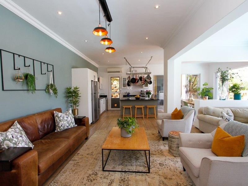 Spacious open-plan living area featuring a modern kitchen with an island, recessed lighting, and neutral finishes, seamlessly flowing into the comfortable lounge space.