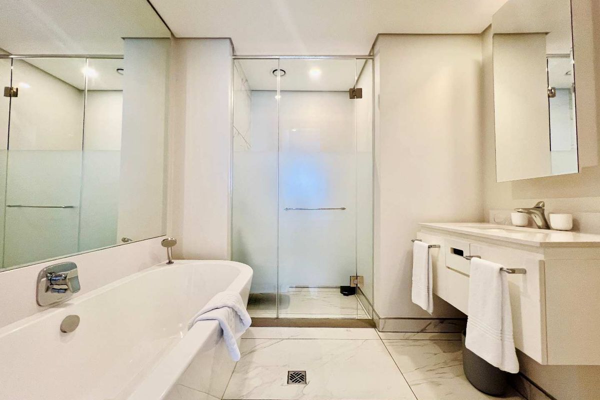 Modern bathroom featuring a sleek freestanding bathtub, a glass-enclosed walk-in shower, and a wall-mounted vanity with marble-look floor tiling.