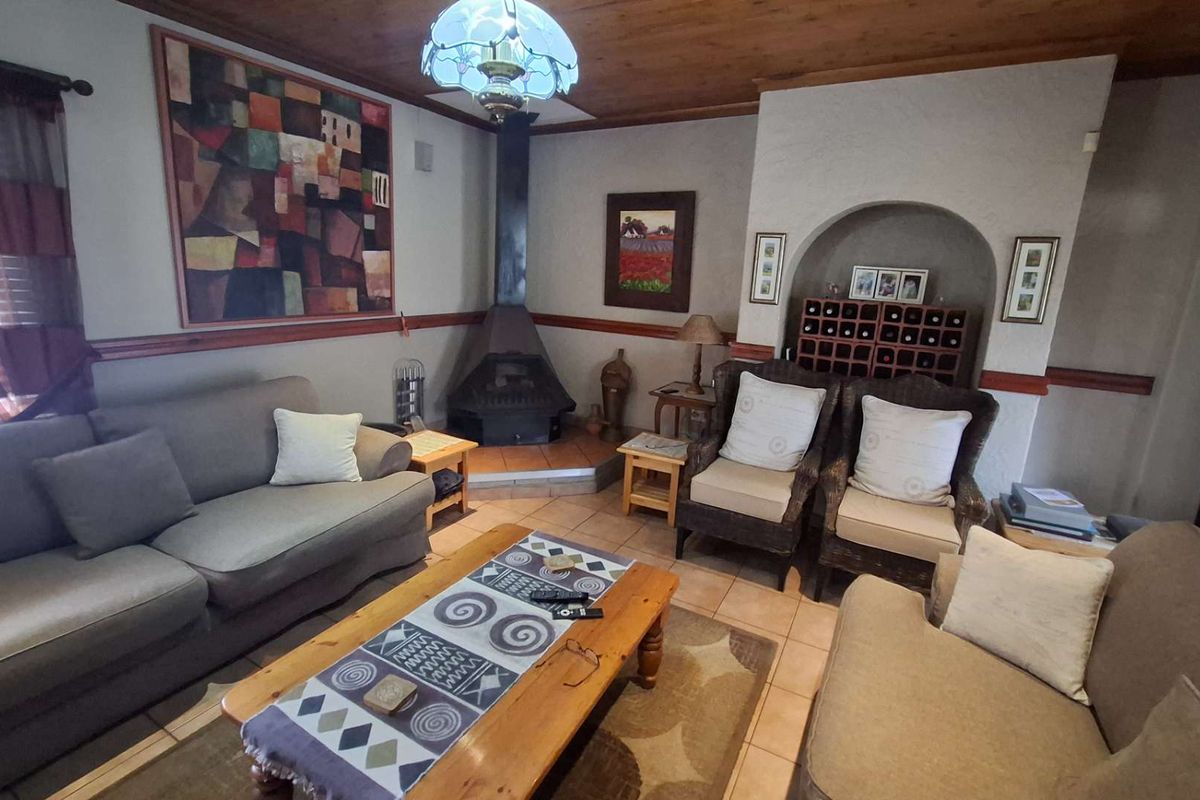 A cozy living room featuring a freestanding fireplace, tiled flooring, a timber ceiling, and a built-in arched alcove with integrated wine storage.