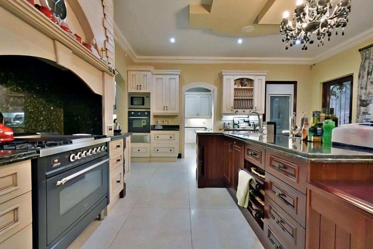 Spacious kitchen featuring a large central island, built-in oven, gas stove with extractor hood, and ample cabinetry, leading into a secondary scullery area.