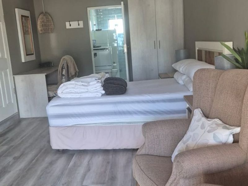 A well-maintained bedroom featuring light-toned laminate flooring, built-in wardrobe storage, and a textured ceiling, offering a comfortable and functional living space.