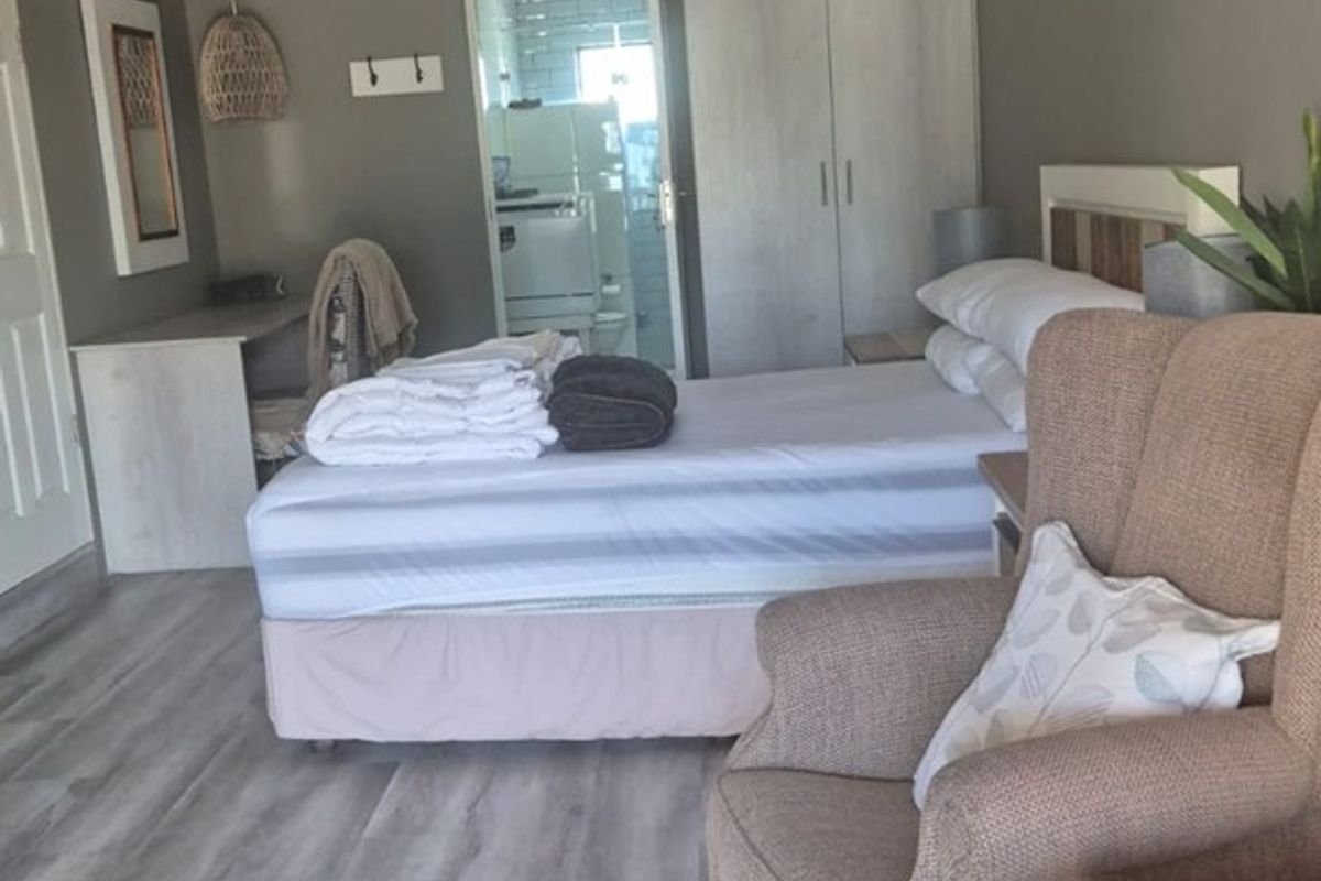 A well-maintained bedroom featuring light-toned laminate flooring, built-in wardrobe storage, and a textured ceiling, offering a comfortable and functional living space.