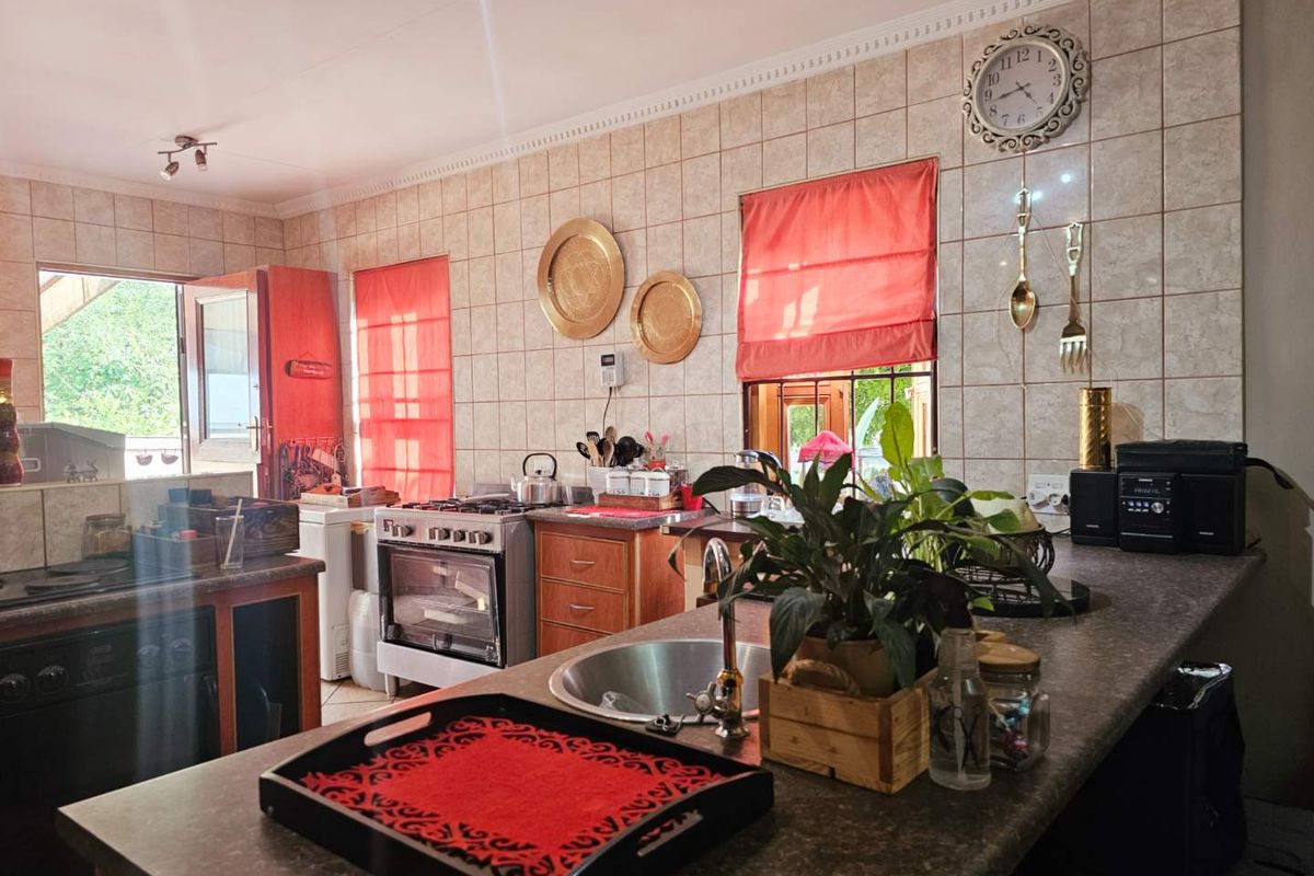 A functional kitchen featuring tiled walls, a central island with a stainless steel sink, and a built-in gas stove with oven.