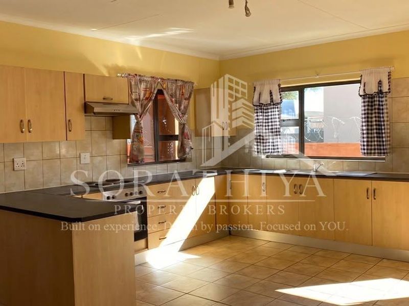 A functional kitchen featuring laminate cabinetry, built-in oven, extractor fan, and tiled splashbacks, offering a clean and practical workspace.