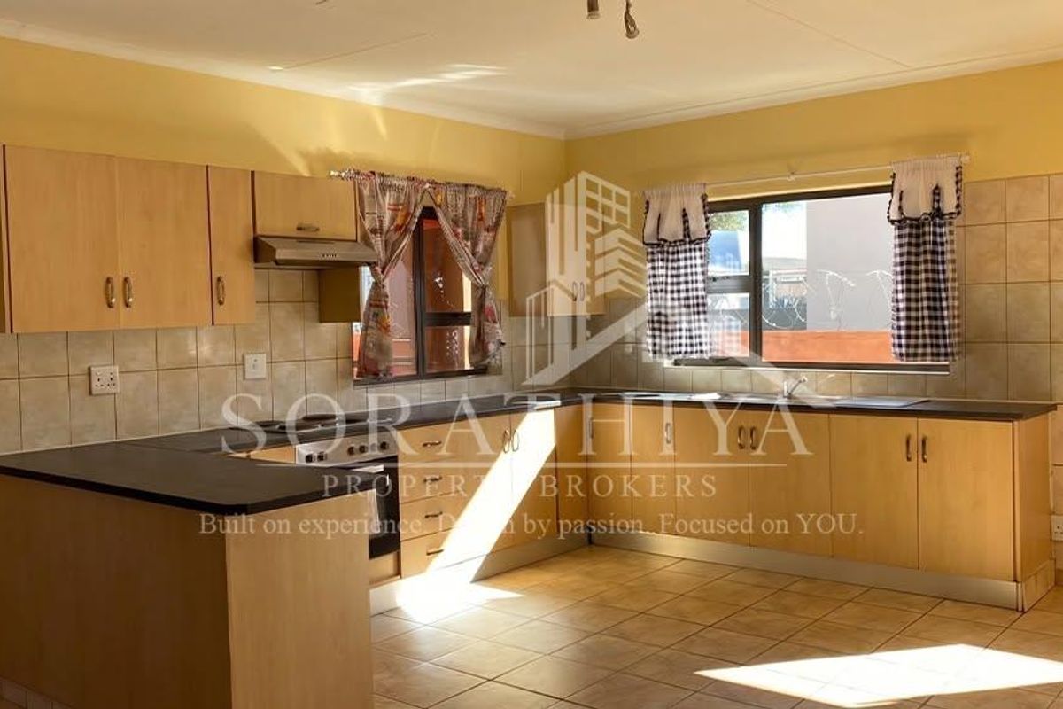 A functional kitchen featuring laminate cabinetry, built-in oven, extractor fan, and tiled splashbacks, offering a clean and practical workspace.