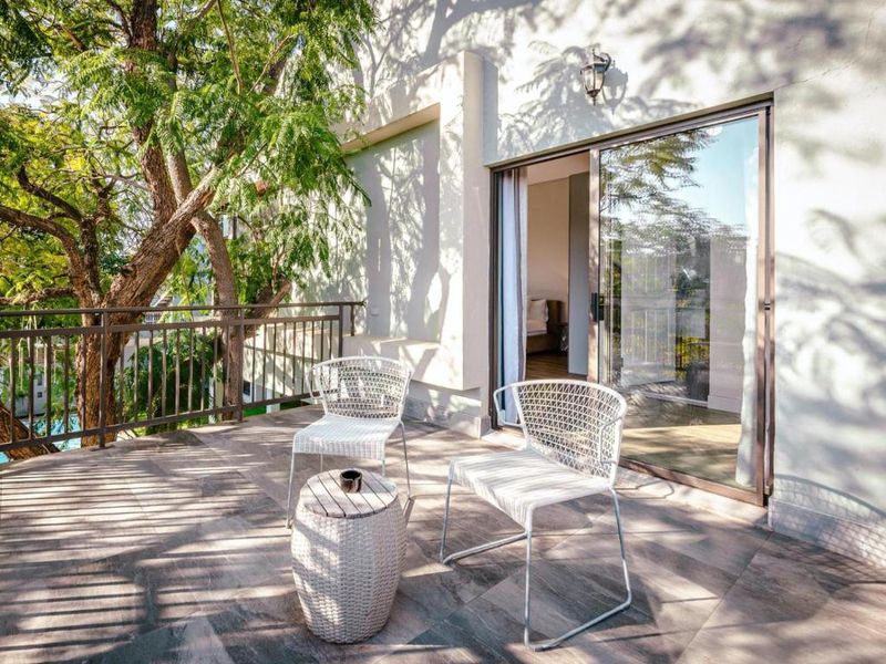 A private balcony featuring tiled flooring, a metal balustrade, and a sliding glass door providing access to the interior living space.