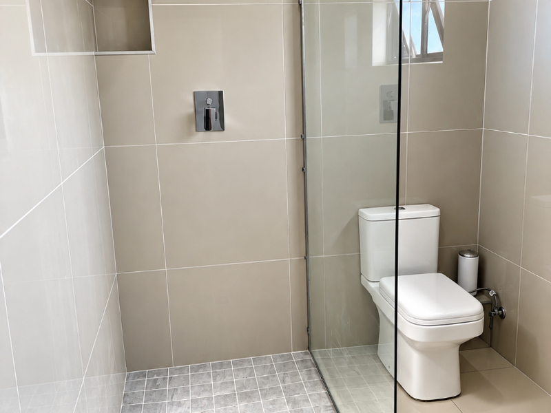 Modern bathroom featuring a walk-in shower with a rain shower head, recessed wall niche, glass screen, and contemporary toilet with neutral wall tiling.