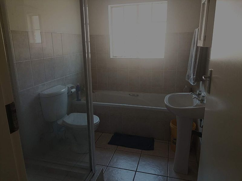 A functional bathroom featuring a pedestal basin, bathtub, and a separate shower enclosure with tiled finishes throughout.