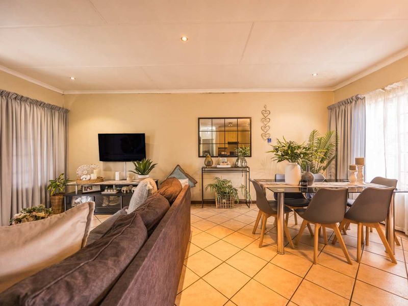 An open-plan living and dining area featuring tiled flooring and recessed downlighting, offering a functional space for relaxation and meals.