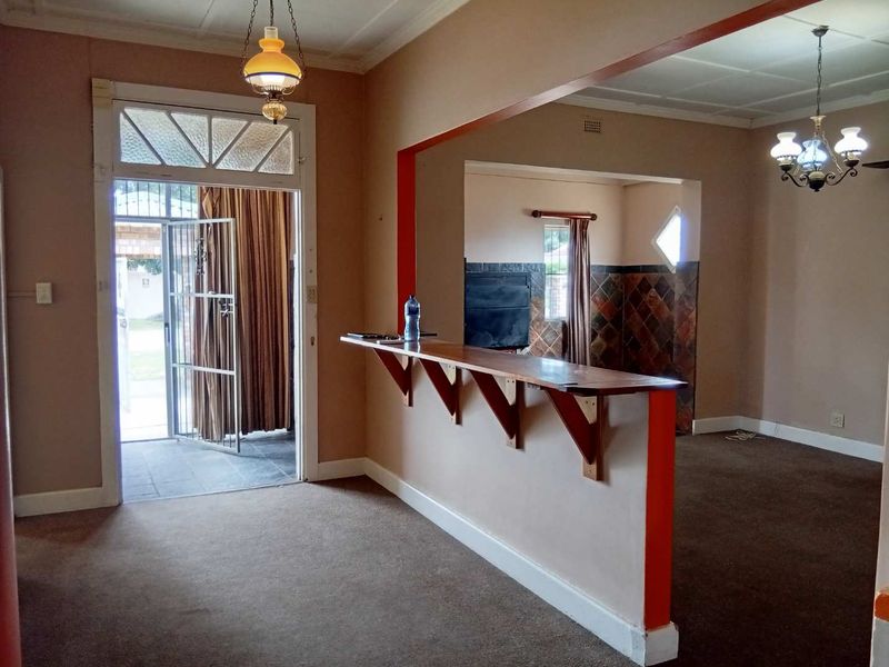 Open plan living area featuring a built-in breakfast bar, security gate access, and neutral wall finishes, offering a versatile space for renovation.