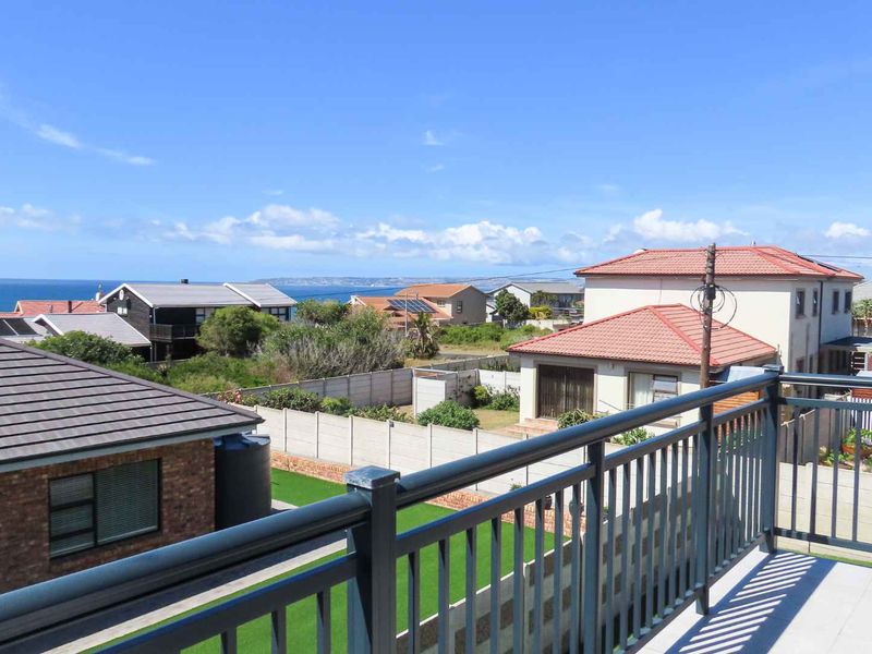 An elevated balcony featuring a metal balustrade with expansive views over the surrounding residential neighborhood and the distant coastline.