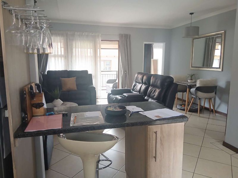 Open-plan living and kitchen area featuring a central island with granite countertop, tiled flooring, and direct access to a balcony through sliding doors.