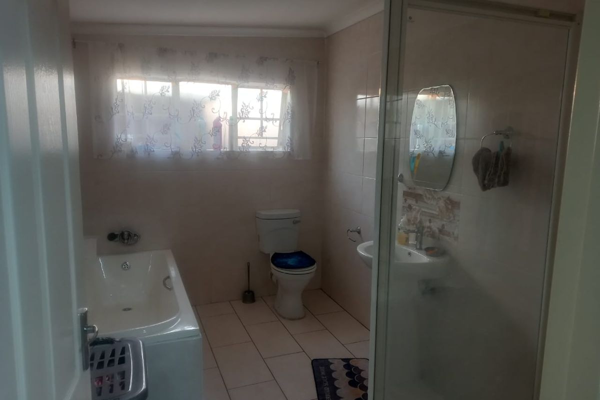 A functional bathroom featuring a built-in bathtub, separate shower enclosure, toilet, and wall-mounted basin with tiled flooring and wall finishes.