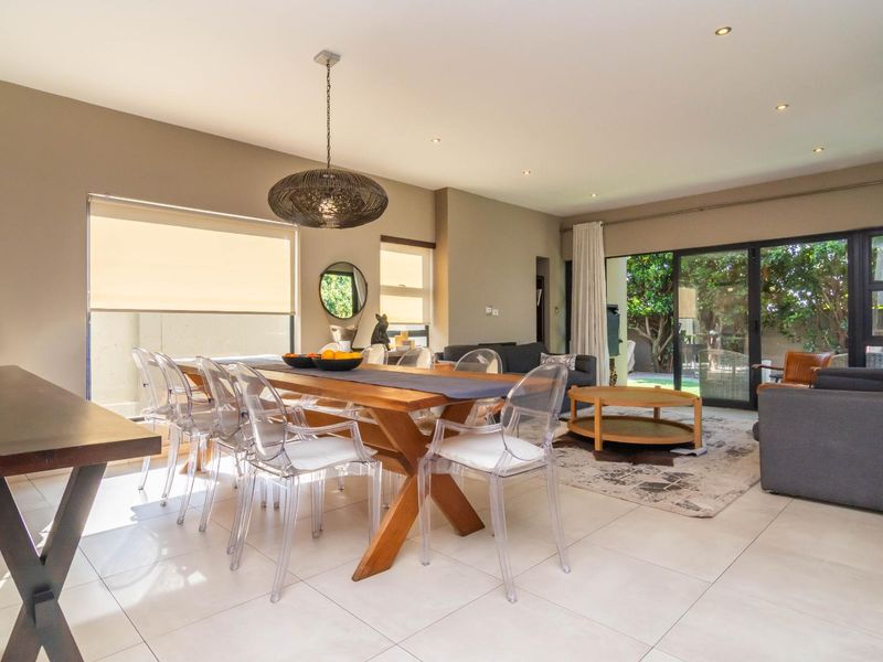 Spacious open-plan living and dining area featuring tiled flooring, recessed downlights, and large sliding glass doors providing seamless access to the outdoor space.