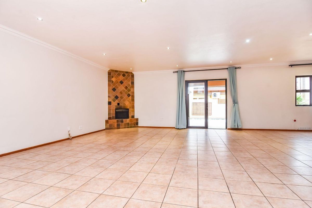 Spacious living area featuring tiled flooring, a built-in fireplace with decorative tiling, and sliding glass doors providing access to the outdoor area.