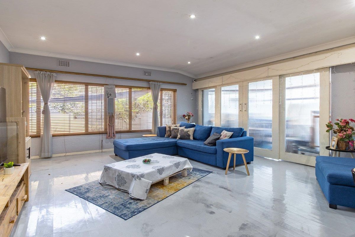 Spacious living room featuring recessed downlights, large windows with timber blinds, and sliding glass doors leading to the exterior.