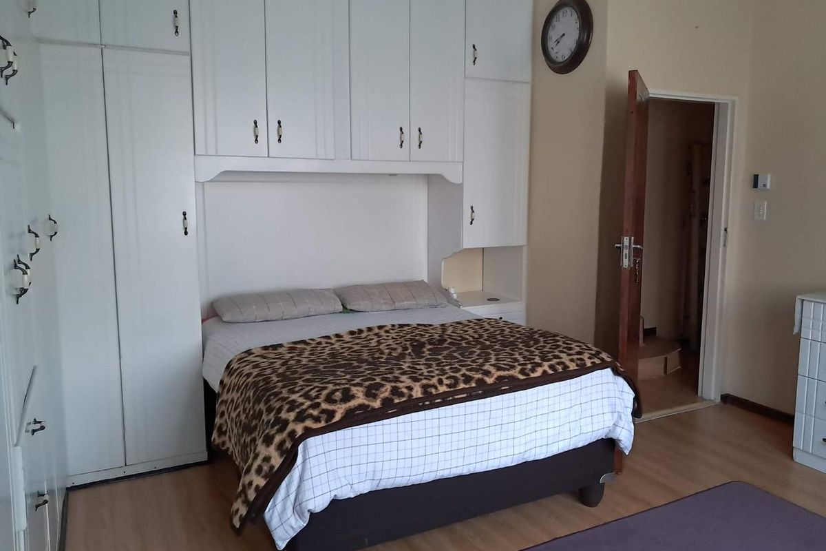 A bedroom featuring extensive white built-in cupboards and laminate flooring, providing ample storage space and a functional layout.
