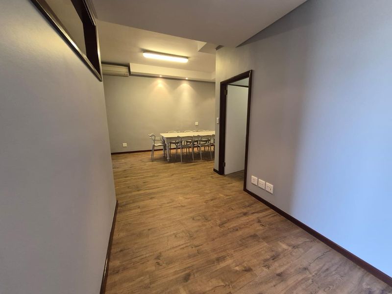 A clean, modern office space featuring wood-look laminate flooring, recessed lighting, and an integrated air conditioning unit.