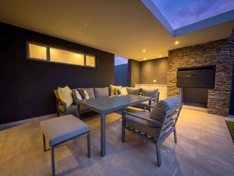 A modern covered patio featuring a built-in braai, stone cladding, recessed lighting, and a skylight, perfect for outdoor entertaining.