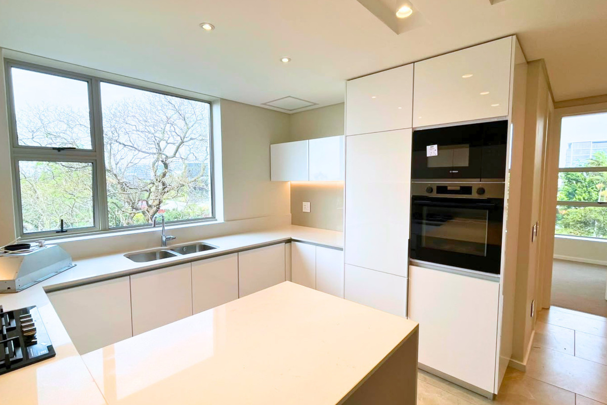 Modern kitchen featuring white cabinetry, quartz countertops, integrated Bosch appliances, gas hob, and large windows providing natural light.