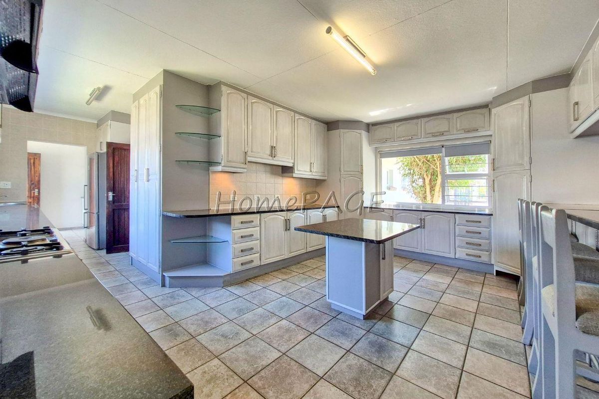Spacious kitchen featuring granite countertops, built-in cabinetry, a central island, and tiled flooring, offering a functional layout for meal preparation.