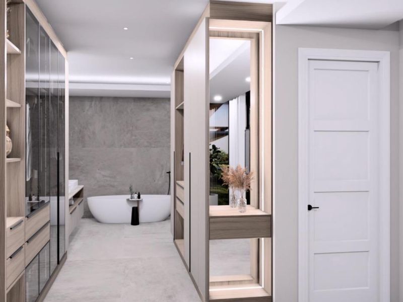 Modern luxury bathroom featuring a sleek freestanding bathtub, extensive built-in cabinetry, and high-end stone finishes with integrated ambient lighting.