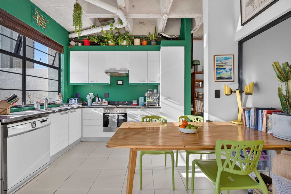 Modern kitchen featuring white cabinetry, exposed concrete ceiling, tiled flooring, and integrated appliances, creating a vibrant and functional culinary space.