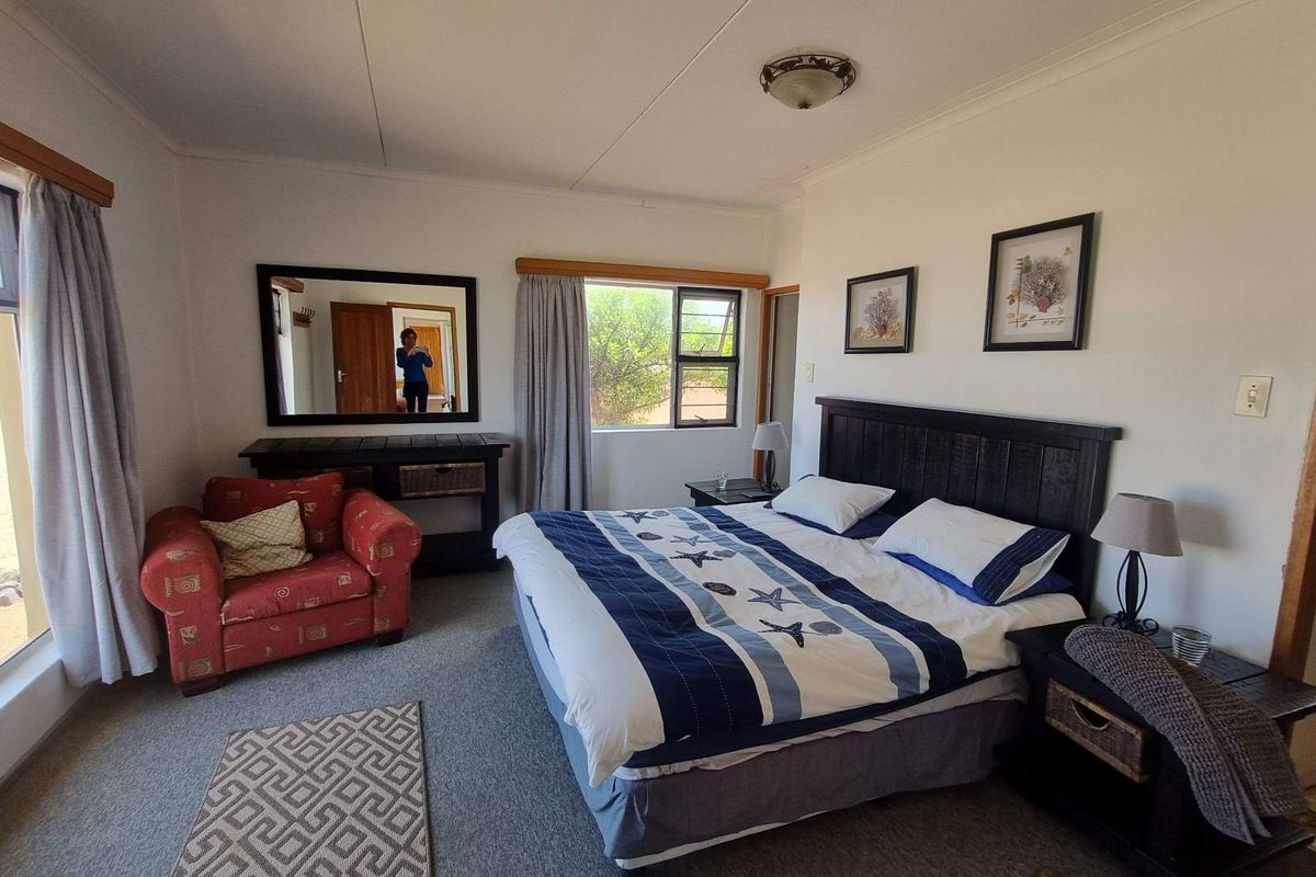 A spacious bedroom featuring carpeted flooring, large windows providing natural light, and neutral wall finishes.