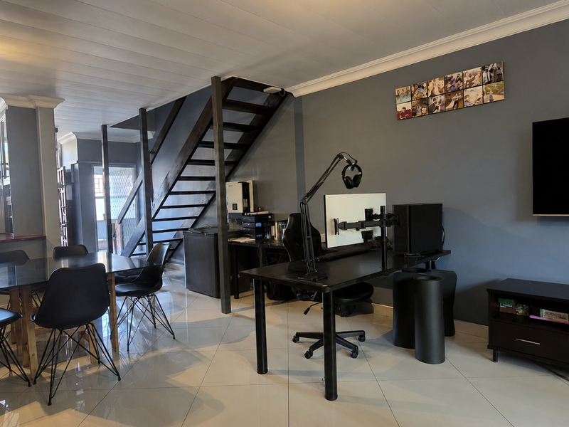 Spacious open-plan living and dining area featuring a modern staircase, tiled flooring, and neutral grey walls, creating a versatile multi-functional space.