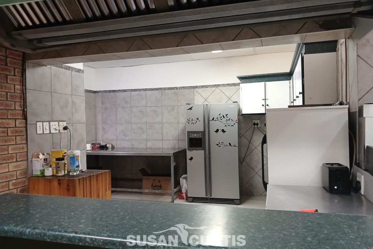 A functional kitchen area featuring a breakfast bar, stainless steel prep surfaces, tiled backsplash, and built-in cabinetry.