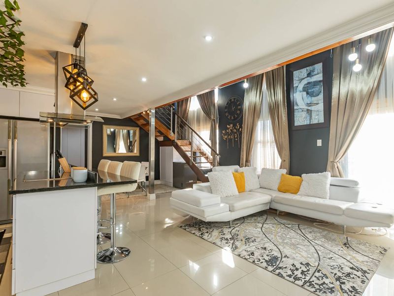 Modern open-plan living area featuring a sleek kitchen with island, tiled flooring, and a staircase leading to the upper level.