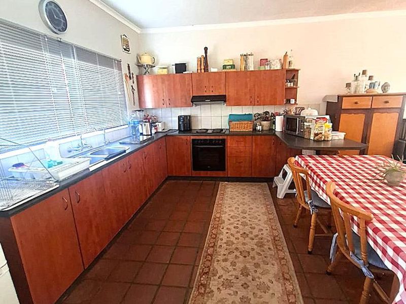 A functional kitchen featuring wood-finish cabinetry, tiled flooring, and integrated appliances, offering a practical layout with ample counter space.