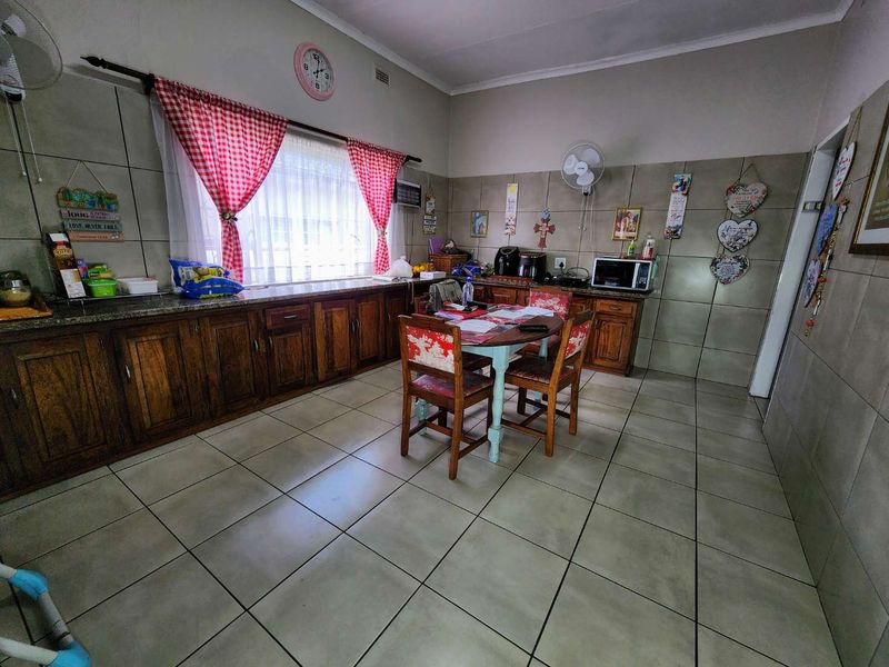 A functional kitchen featuring wooden cabinetry, granite countertops, and tiled finishes throughout, offering a practical layout for daily meal preparation.