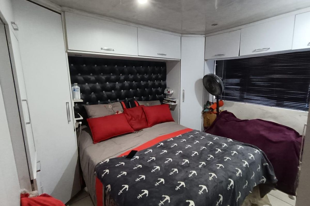 A compact bedroom featuring extensive built-in cabinetry, overhead storage, and a tufted headboard, providing efficient use of space.