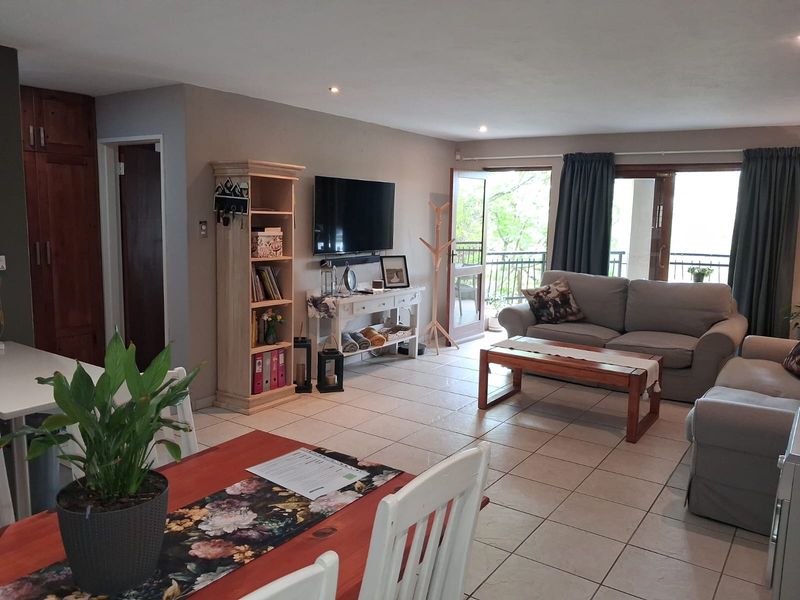 Open-plan living and dining area featuring tiled floors, recessed lighting, and direct access to a private balcony through sliding glass doors.