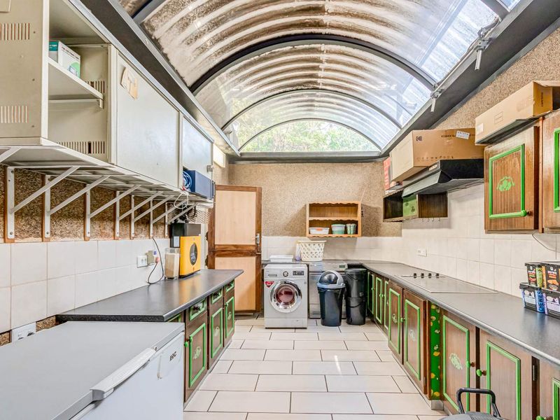 Functional laundry room featuring extensive built-in cabinetry, tiled flooring, and a distinctive barrel-vaulted skylight providing ample natural light.